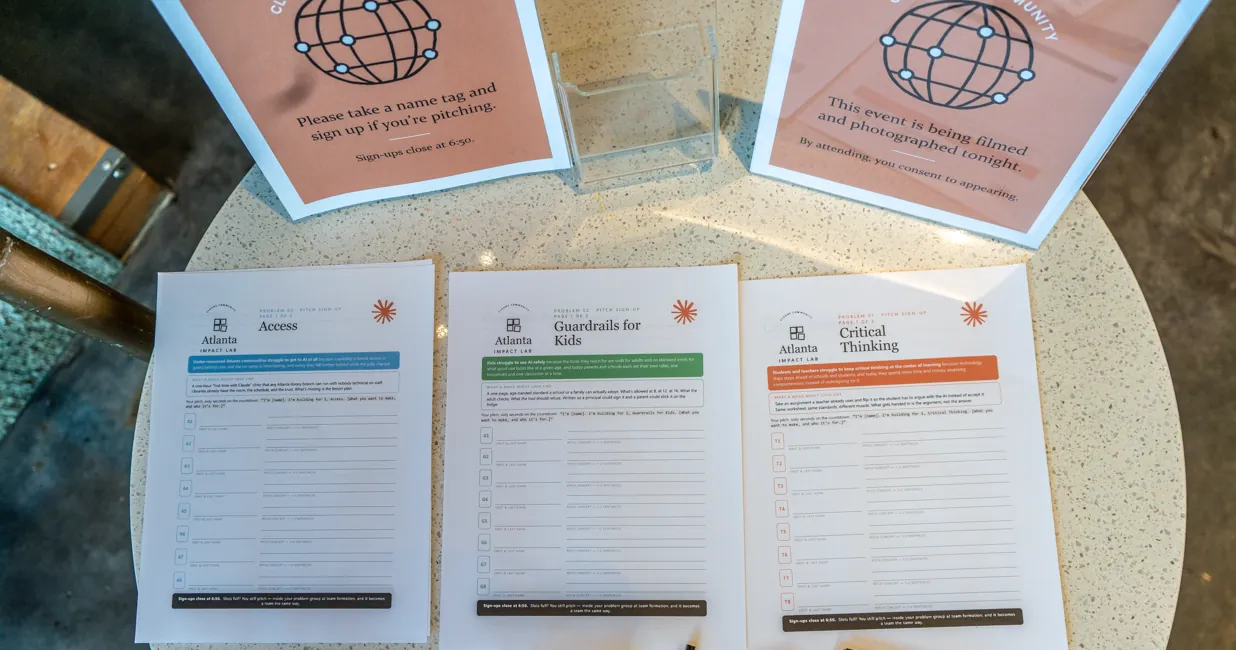 Three pitch sign-up sheets on a table, one each for Access, Guardrails for Kids and Critical Thinking, under signs asking pitchers to sign up and noting the event is being filmed.