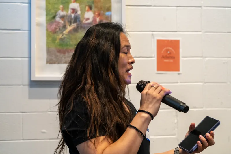 An attendee pitching into a microphone while reading notes from a phone.