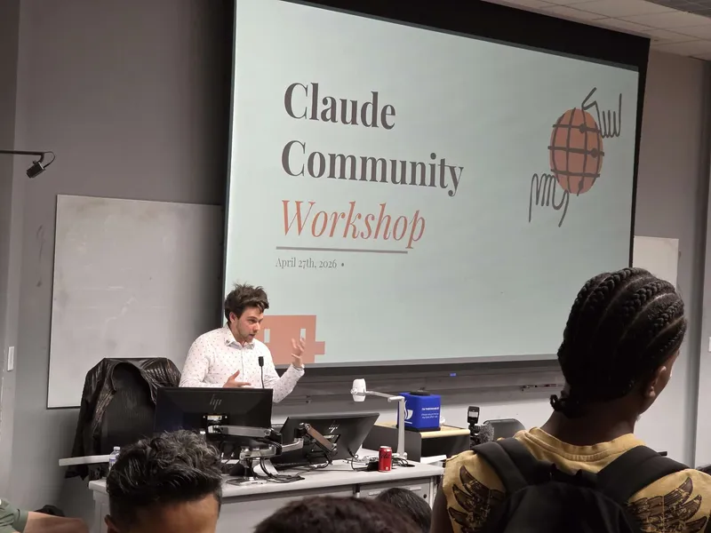 Speaker presenting at the Claude Community Workshop, with the title slide projected behind