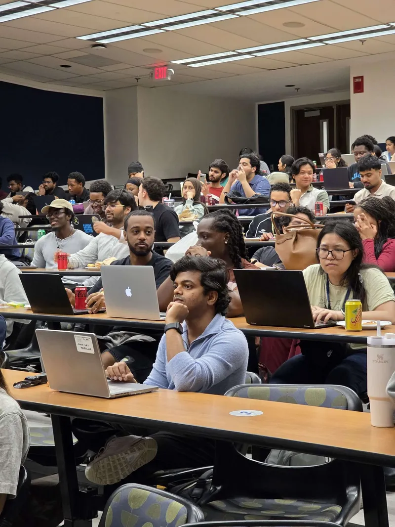 Attendees with laptops filling a university lecture hall during a Claude workshop