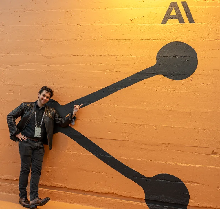 Tyler Sztuka pointing at the Anthropic logo at a Claude Community event
